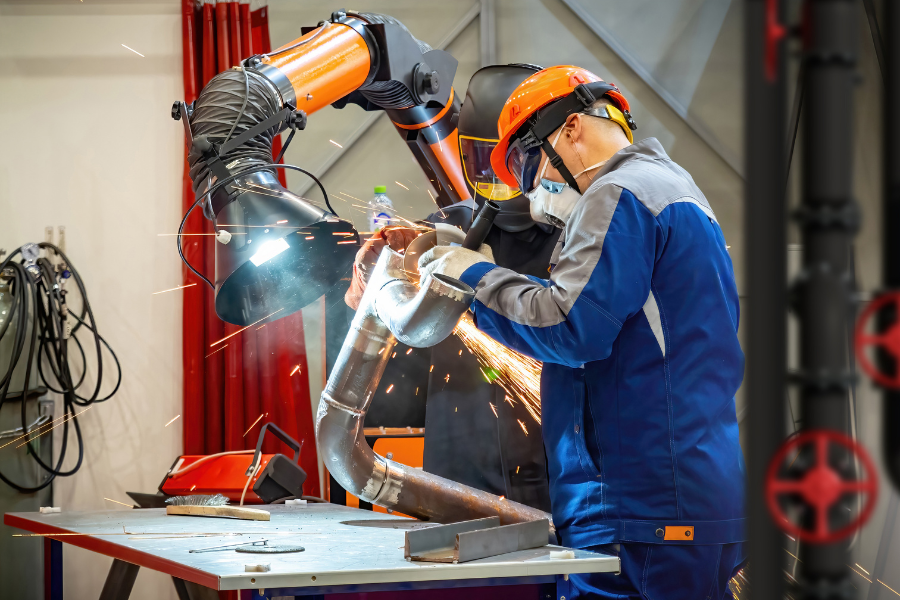Two workers soldering steel pipe
