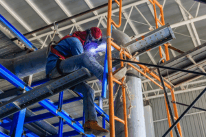 Worker welding piping in protective mask